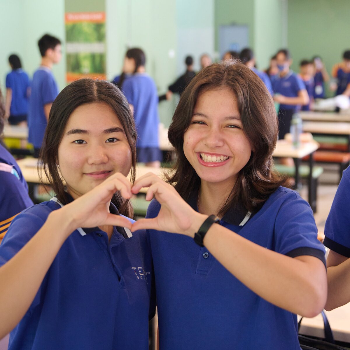 Girl smiling and making a heart with their hands