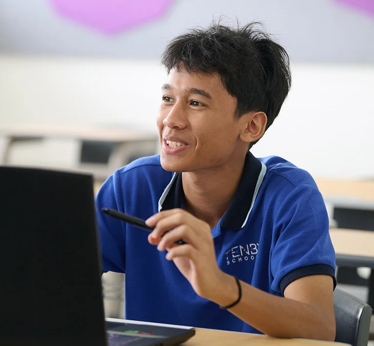 Tenby Schools student smiling while using a computer