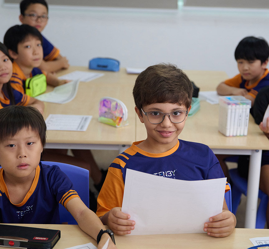 Tenby Schools student smiling while holding a paper sheet