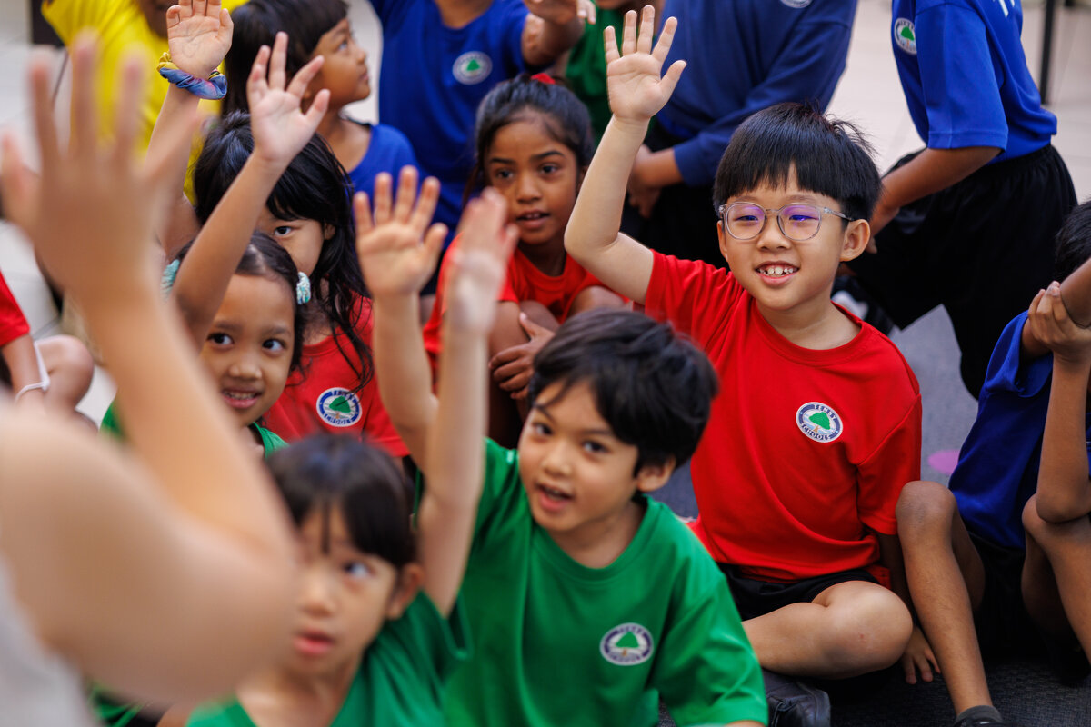 Young students smiling and raising their hands