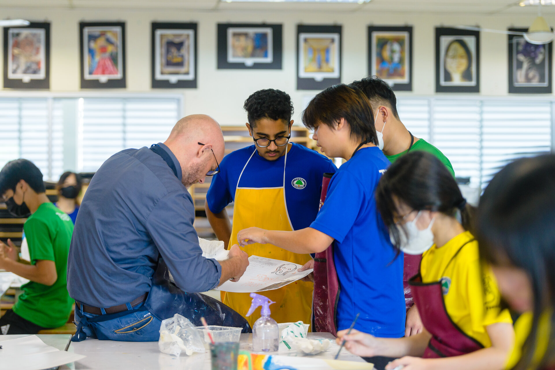 Students talking with their teacher about a drawing